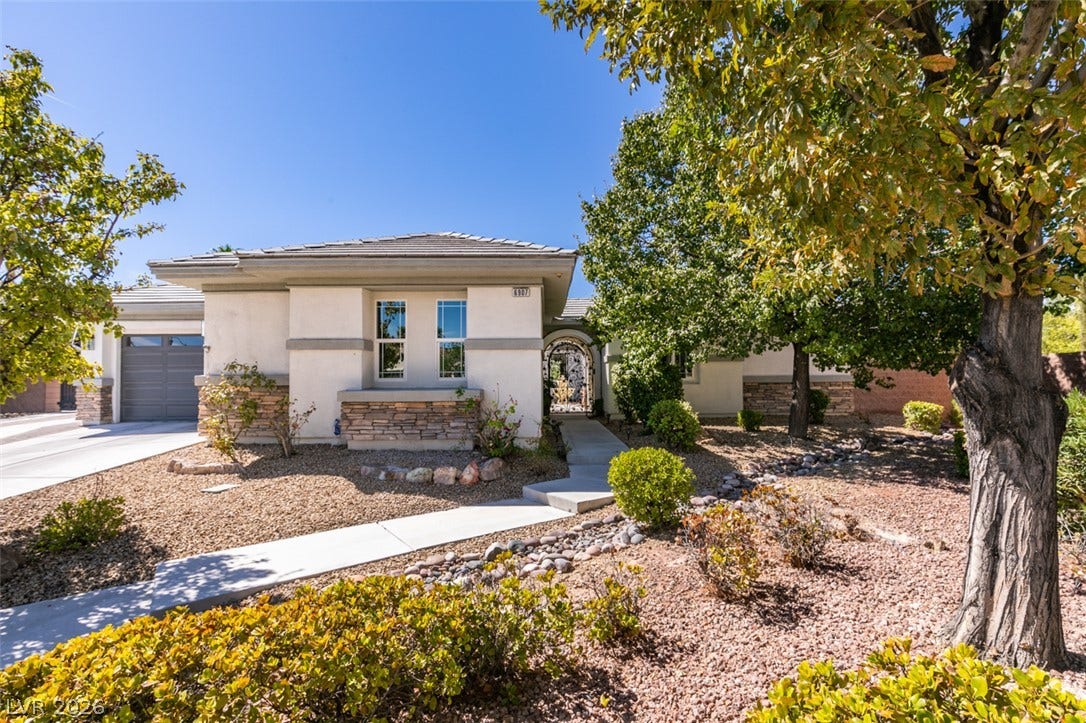 Mature trees frame the architectural lines and stone accents of this modern exterior design.