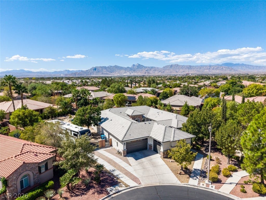 A tiled roof and spacious driveway highlight this residence set against a mountain backdrop.