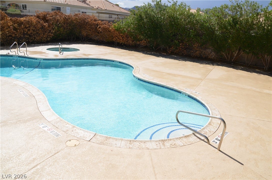 773 Cathy Lane, Henderson, NV 89015 A curved inground pool and integrated spa sit surrounded by a concrete patio.