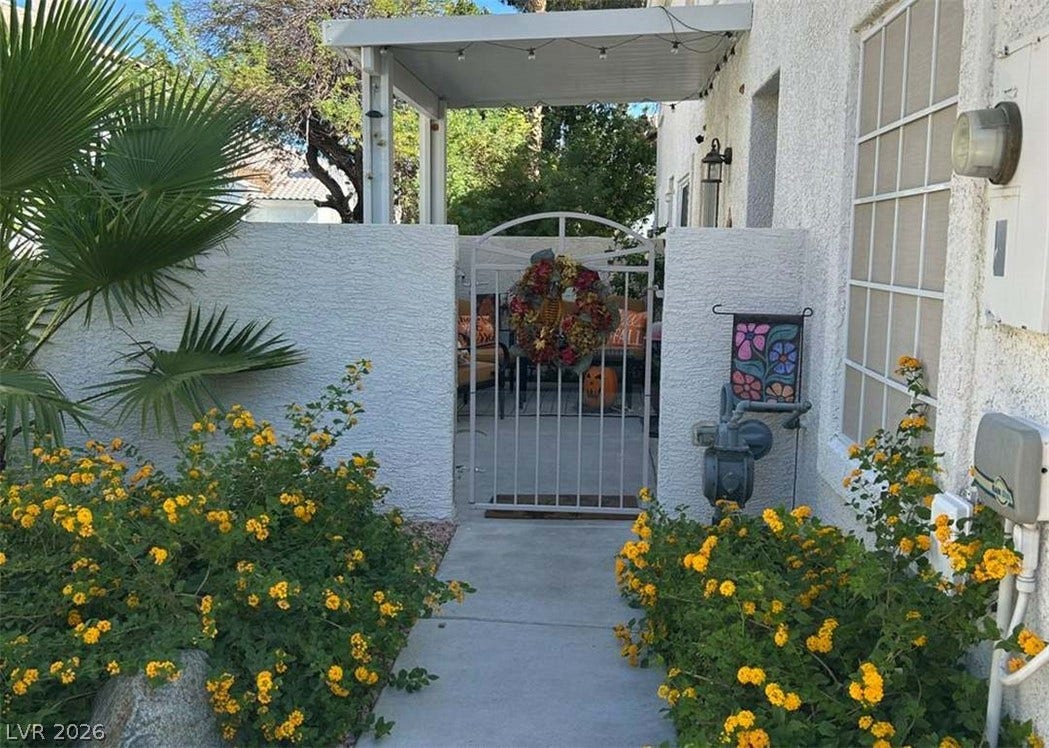 Lush landscaping frames the concrete walkway leading to a gated entry courtyard.