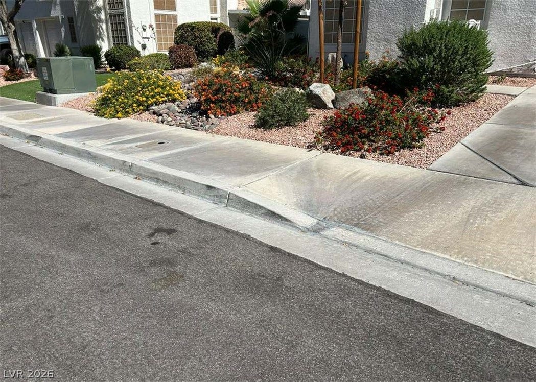 Lush desert landscaping and paved sidewalks border the front of this residential property.