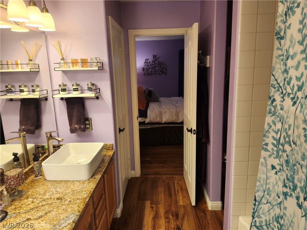 Rich wood flooring connects this bathroom vanity area directly to the adjoining bedroom.