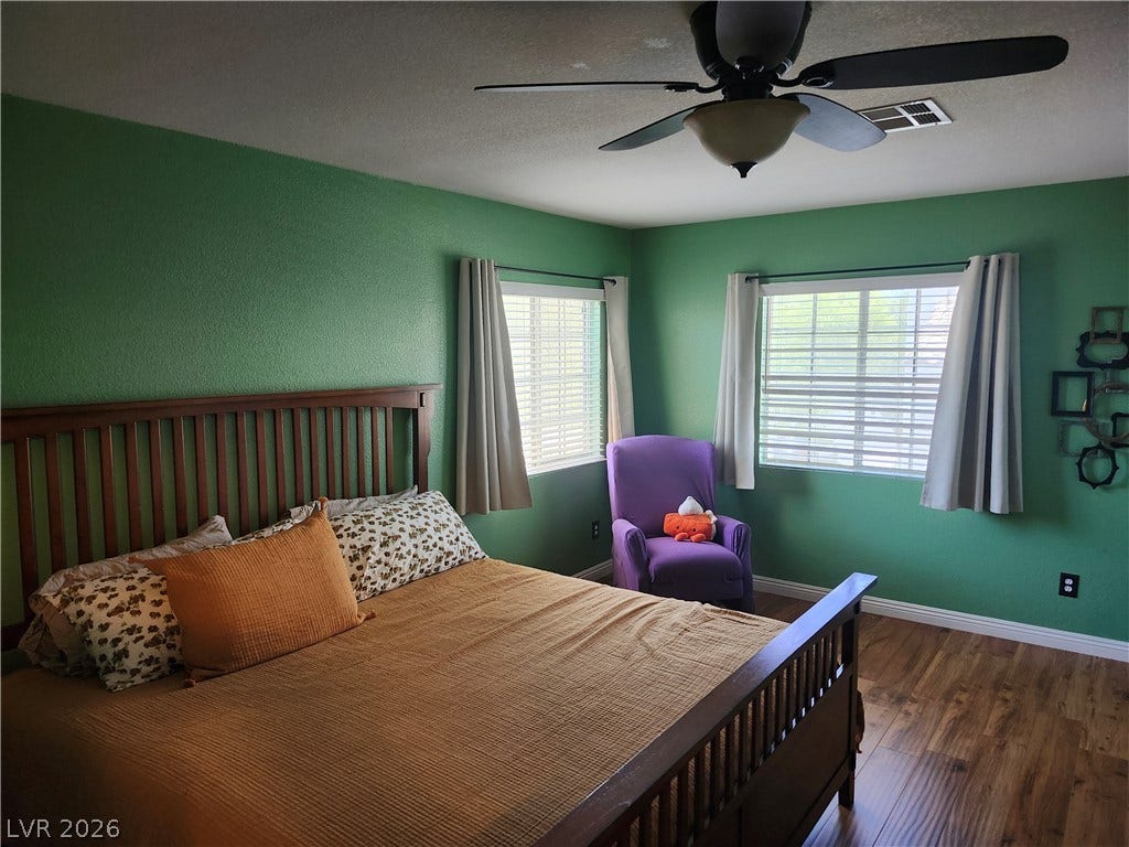 Gleaming wood-look floors anchor this comfortable bedroom featuring dual windows that welcome natural light.