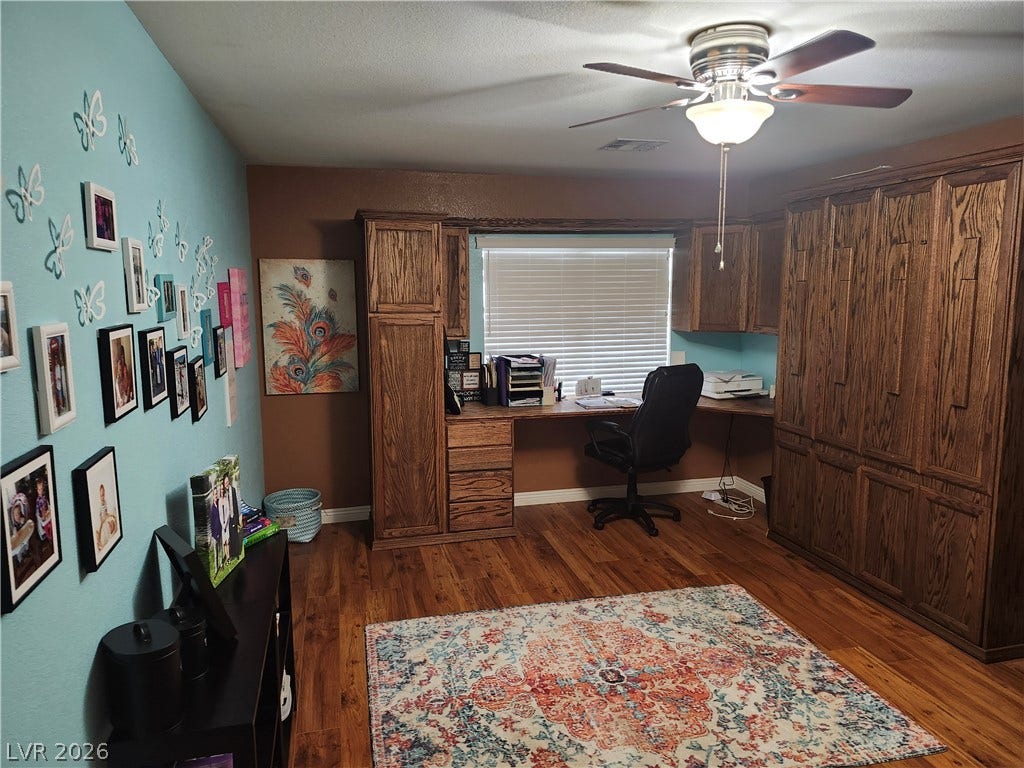 Rich hardwood flooring complements the custom oak cabinetry in this versatile workspace.