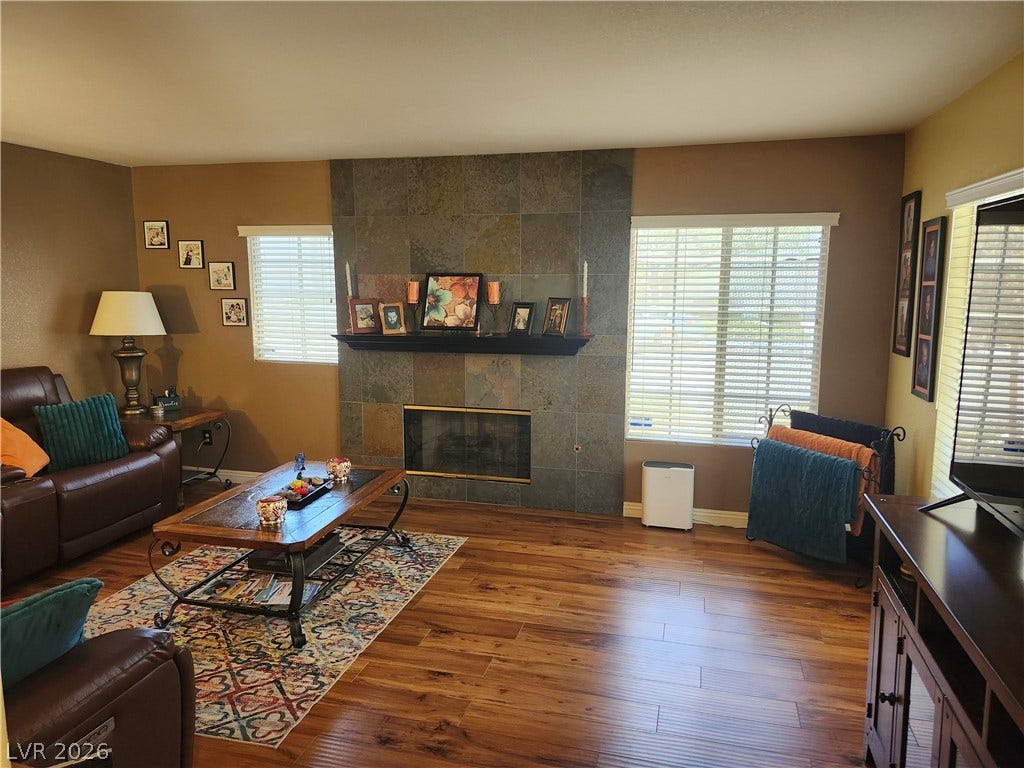 Rich wood flooring anchors this inviting space highlighted by a floor-to-ceiling tiled fireplace.