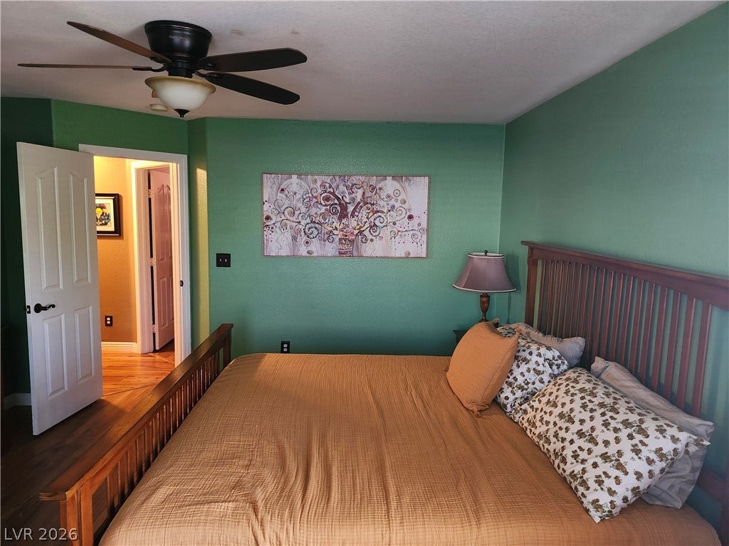 Gleaming hardwood floors run through a comfortable bedroom with a smooth ceiling.