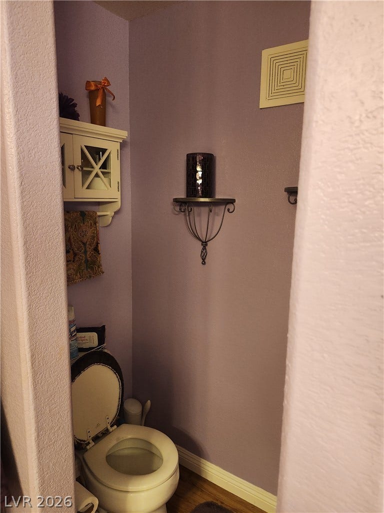 An intimate bathroom alcove features textured walls and a neat storage cabinet.