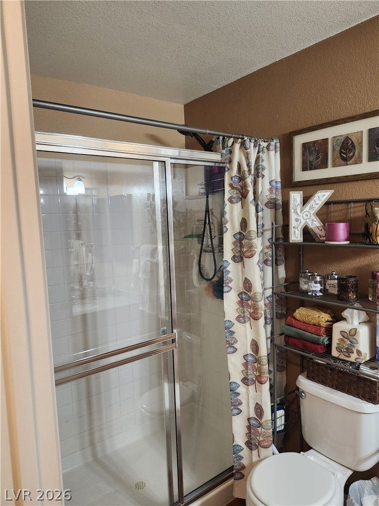 A glass-enclosed walk-in shower stands adjacent to a classic white toilet.