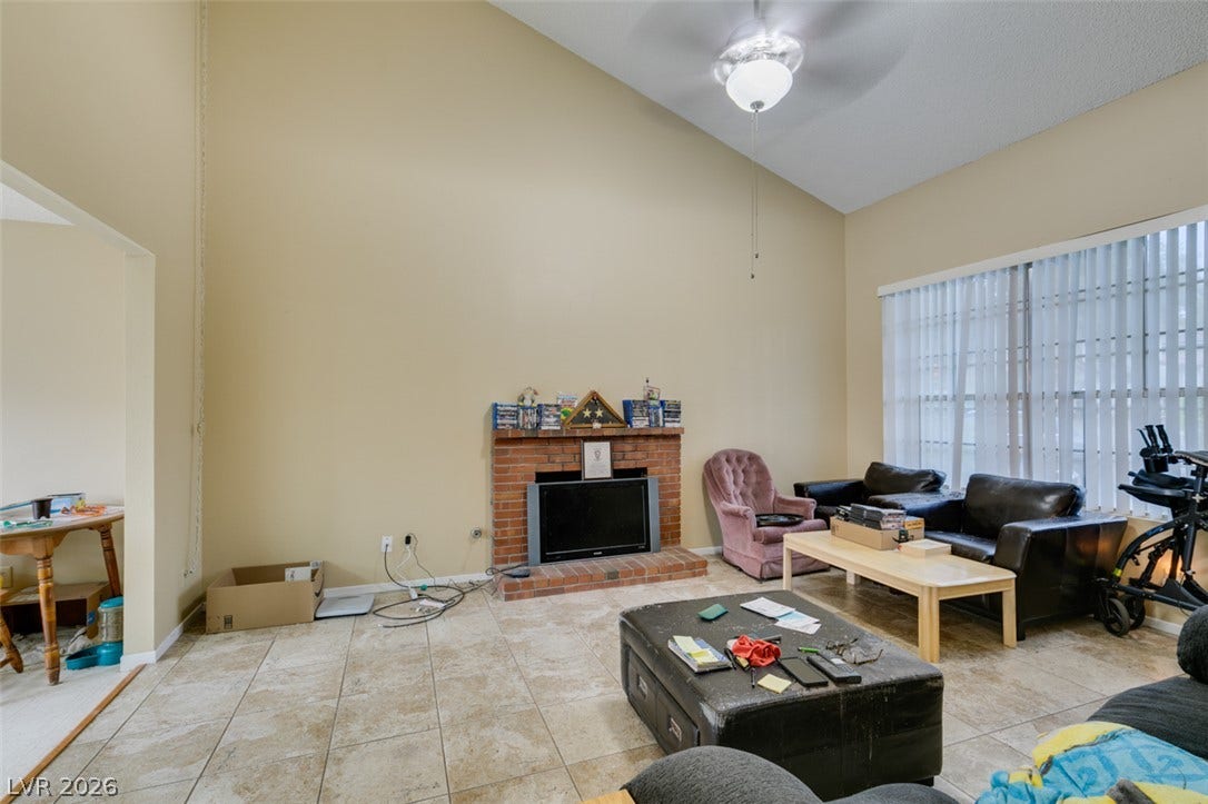 Soaring vaulted ceilings and a brick fireplace highlight this tiled living space.