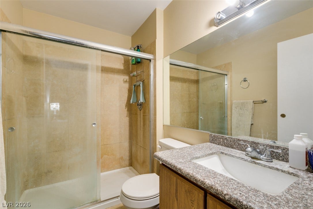 Polished granite counters and a glass-enclosed shower highlight this functional bathroom.