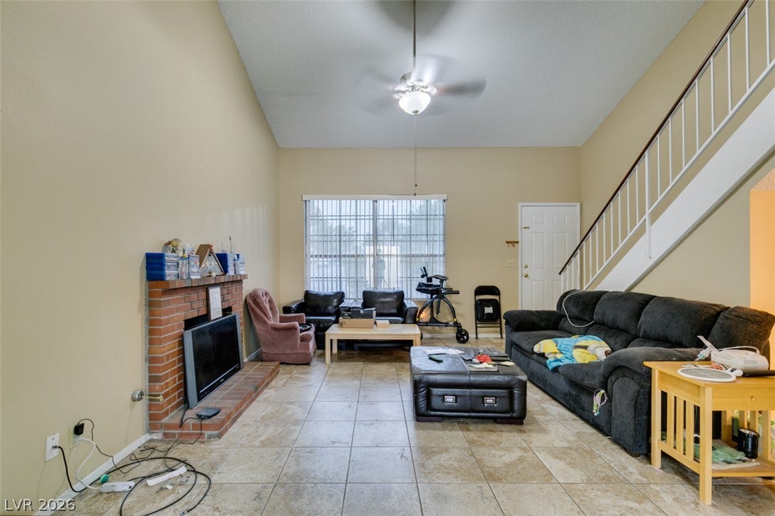 Vaulted ceilings soar over tile flooring and a classic brick fireplace in this living space.