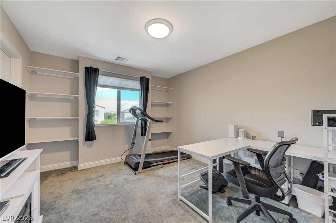 6629 Rockhouse Street, North Las Vegas, NV 89086 Built-in shelving flanking the window highlights this versatile room featuring soft carpeted flooring.