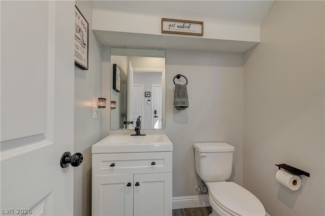 6629 Rockhouse Street, North Las Vegas, NV 89086 A classic white vanity sits under a large wall mirror in this updated half bath.