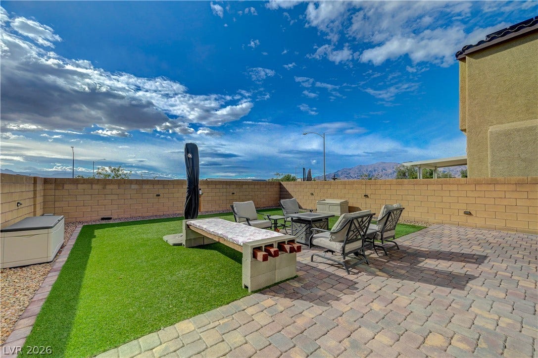 6629 Rockhouse Street, North Las Vegas, NV 89086 An inviting paver patio extends to a tidy lawn area enclosed by stone block fencing.