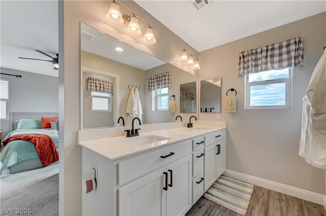 6629 Rockhouse Street, North Las Vegas, NV 89086 A spacious double vanity with white cabinetry and dark fixtures sits on wood-look flooring.