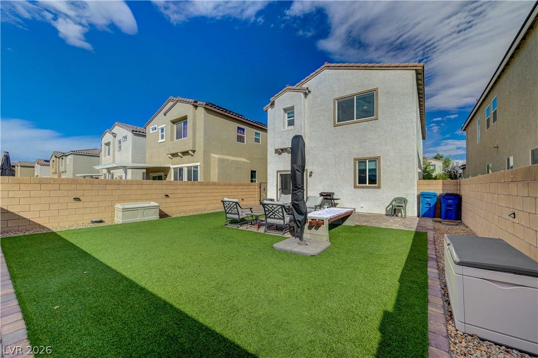 6629 Rockhouse Street, North Las Vegas, NV 89086 Block walls frame a private rear yard featuring a paved patio and lawn area.
