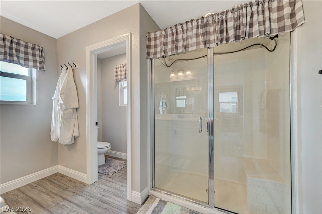 6629 Rockhouse Street, North Las Vegas, NV 89086 Wood-look tile flooring and a glass-enclosed shower stall with bench seating anchor this primary bath.