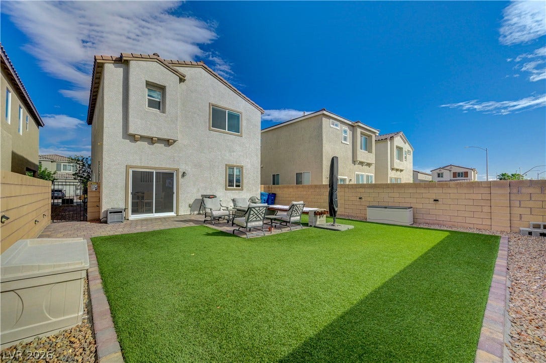 6629 Rockhouse Street, North Las Vegas, NV 89086 A spacious block-walled backyard features a level lawn area and a paved patio space.
