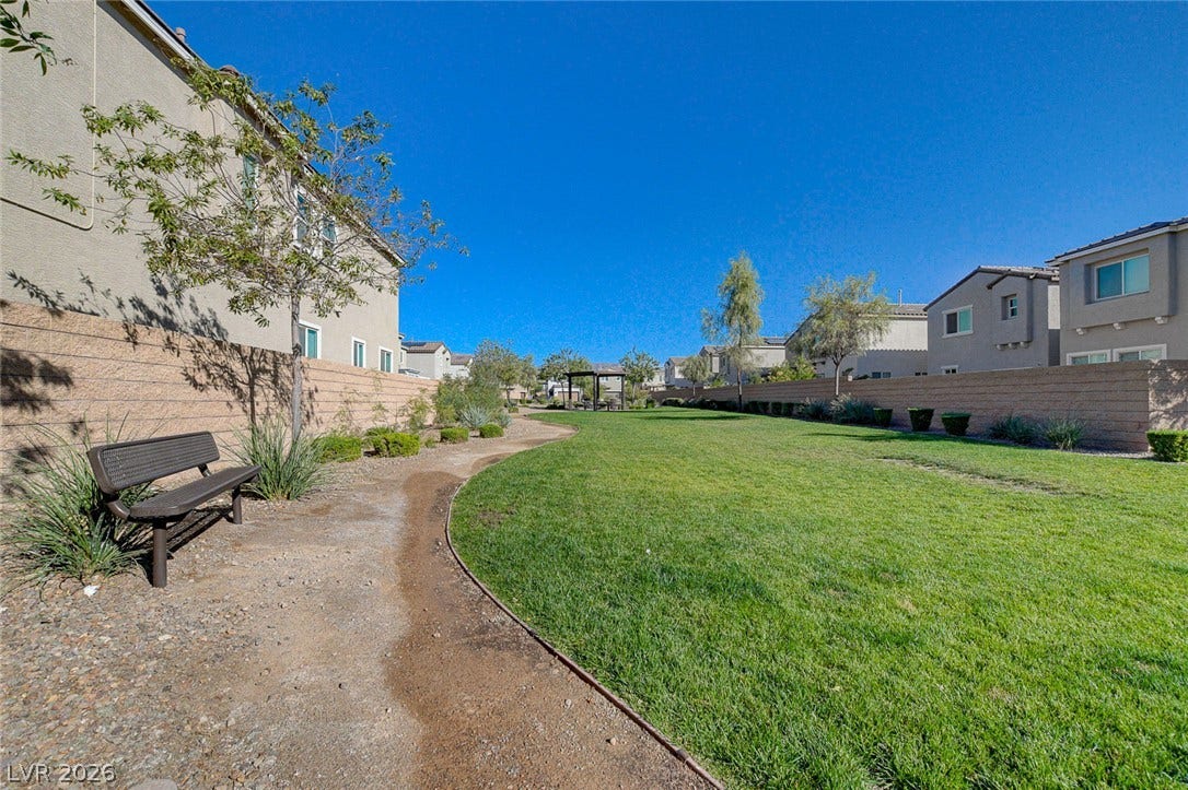 6629 Rockhouse Street, North Las Vegas, NV 89086 A winding path borders a manicured green space lined by block walls and neighborhood homes.
