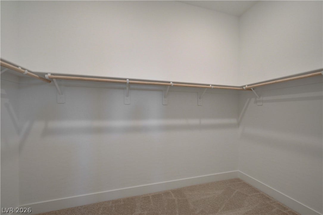 5689 Searching Bear Court, Las Vegas, NV 89149 A spacious walk-in closet offers ample storage with convenient hanging rods and soft carpet flooring.