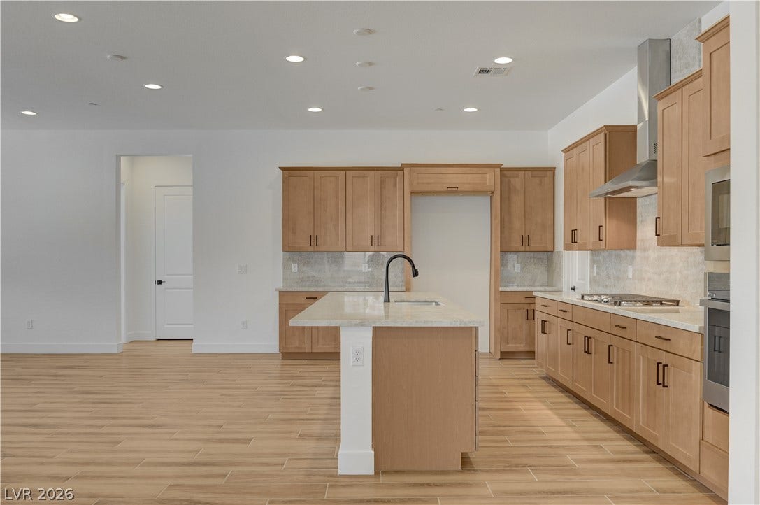 5689 Searching Bear Court, Las Vegas, NV 89149 A contemporary kitchen features light wood cabinetry, recessed lighting, and a spacious island with a sink.