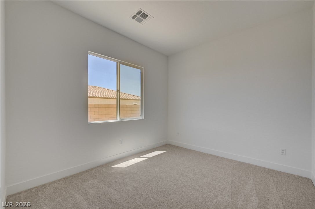 5689 Searching Bear Court, Las Vegas, NV 89149 A well-lit bedroom features plush carpeting and a bright window offering neighborhood views.