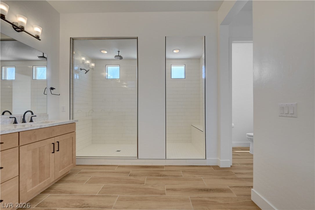 5689 Searching Bear Court, Las Vegas, NV 89149 Luxurious bathroom features a spacious dual shower and elegant wood-look tile flooring.