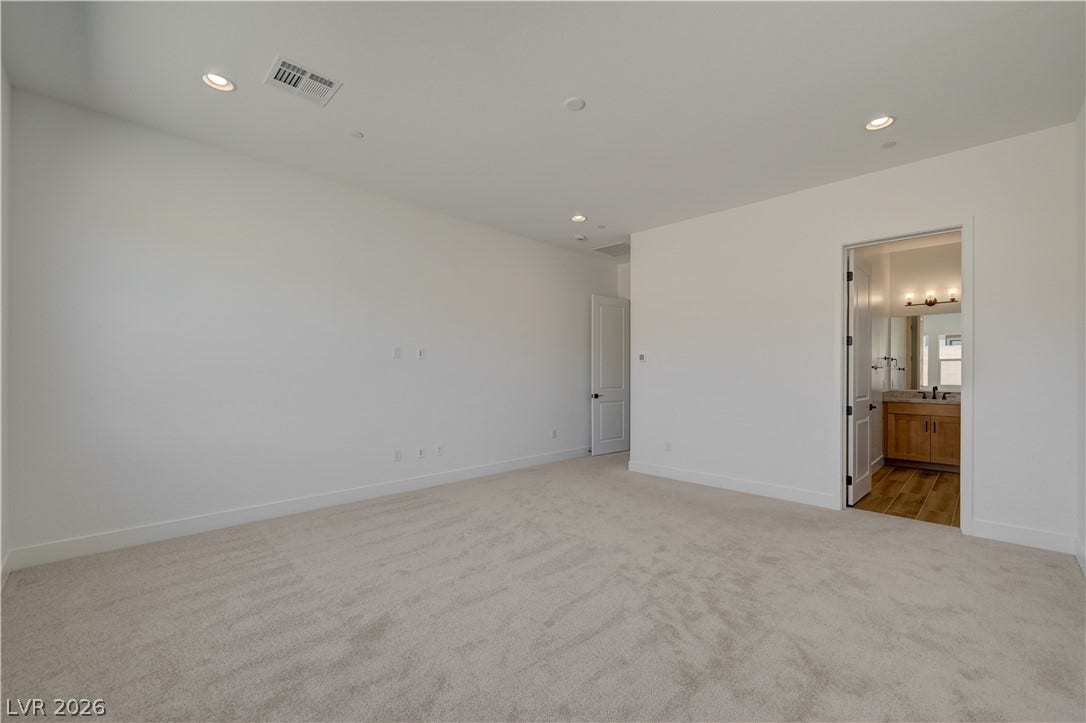 5689 Searching Bear Court, Las Vegas, NV 89149 A spacious bedroom with plush carpeting provides a tranquil retreat, offering direct access to a well-appointed primary bathroom.