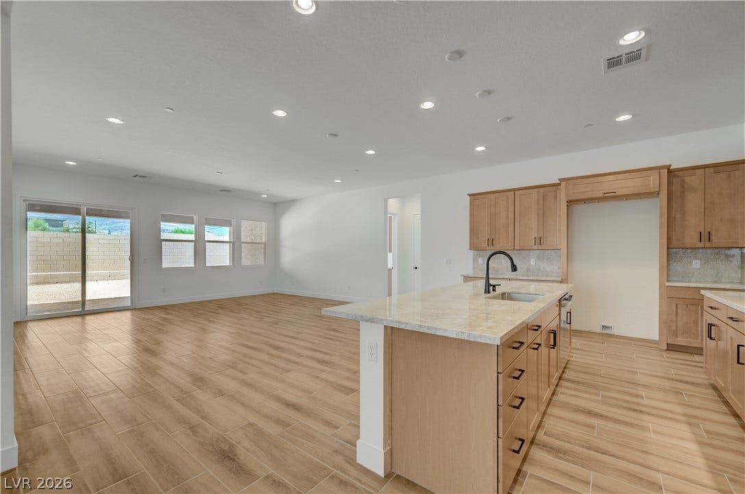 5689 Searching Bear Court, Las Vegas, NV 89149 An open-concept living area boasts a modern kitchen island, wood-look tile flooring, and abundant natural light.
