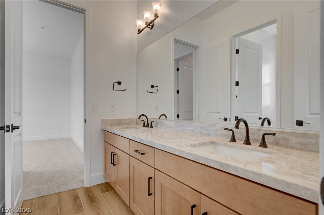 5689 Searching Bear Court, Las Vegas, NV 89149 Double vanity with stone counters and modern fixtures enhances this elegant bathroom.