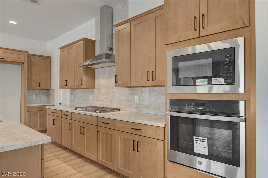 5689 Searching Bear Court, Las Vegas, NV 89149 A well-appointed kitchen features natural wood cabinetry and a suite of stainless steel appliances.