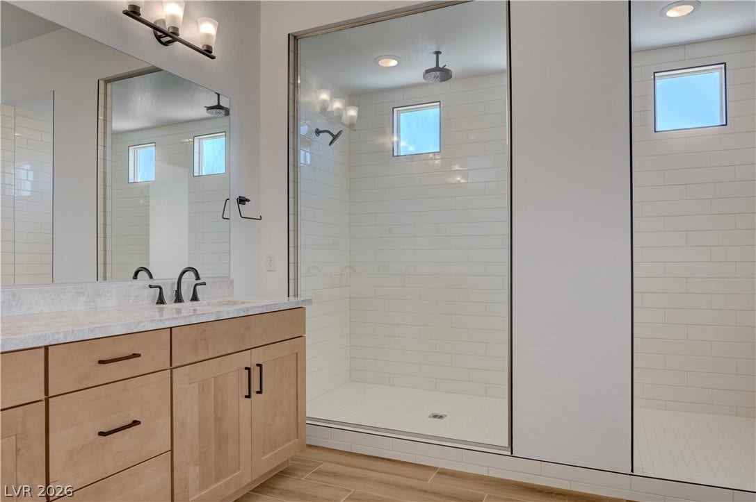 5689 Searching Bear Court, Las Vegas, NV 89149 A well-lit bathroom with a double vanity and sleek glass-enclosed shower, perfect for unwinding.
