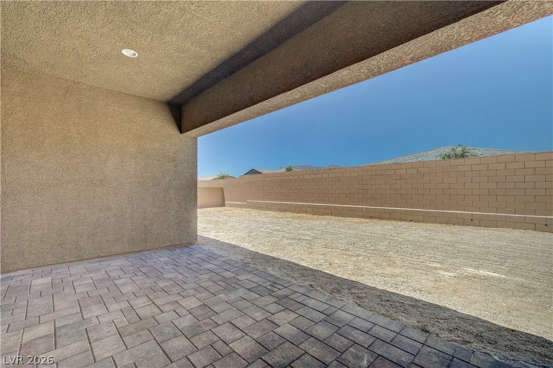 5689 Searching Bear Court, Las Vegas, NV 89149 A spacious covered patio with paver flooring extends to a gravel yard, enclosed by a privacy block wall.