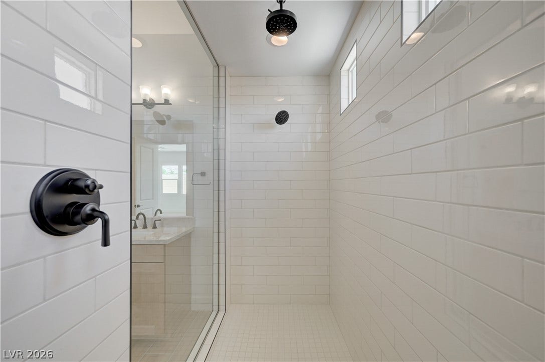 5689 Searching Bear Court, Las Vegas, NV 89149 A spacious, glass-enclosed shower boasts sleek subway tile and contemporary fixtures.