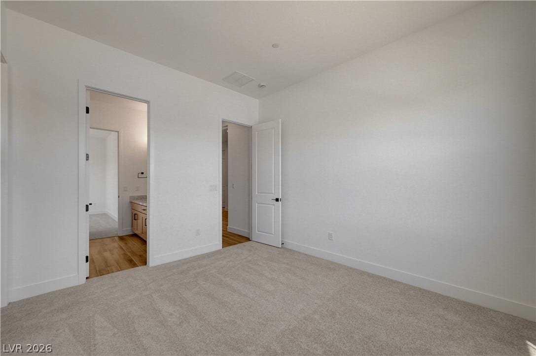 5689 Searching Bear Court, Las Vegas, NV 89149 A well-lit bedroom features plush carpeting and convenient access to a private bathroom.
