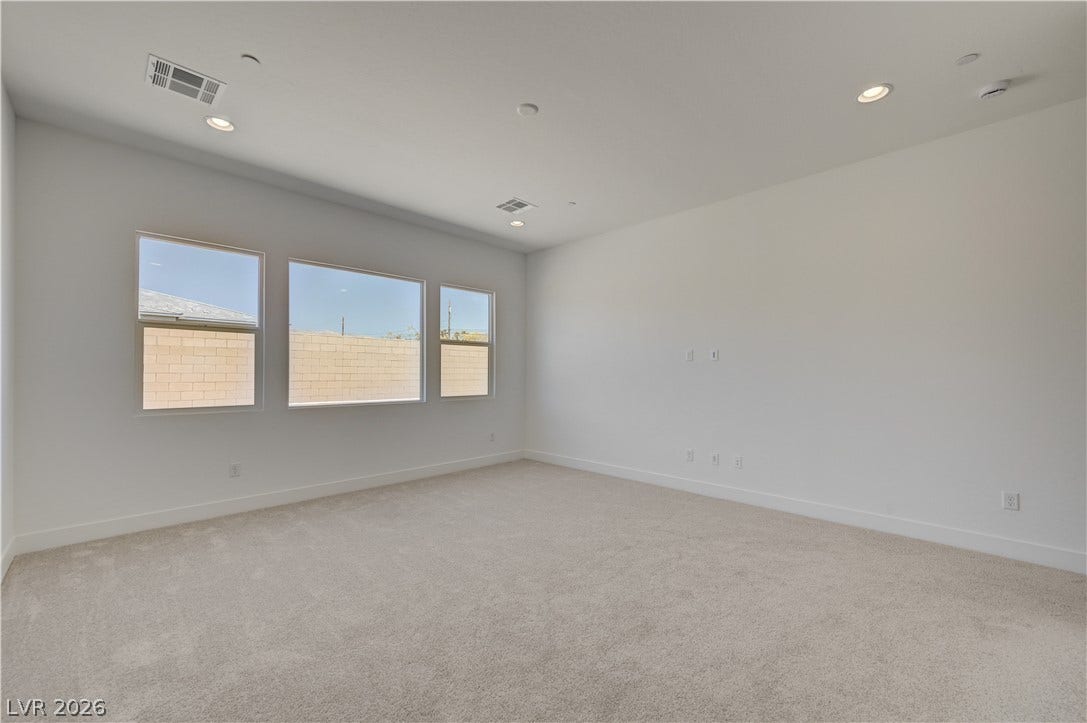 5689 Searching Bear Court, Las Vegas, NV 89149 A spacious, naturally illuminated room features light carpeting and modern recessed lighting.