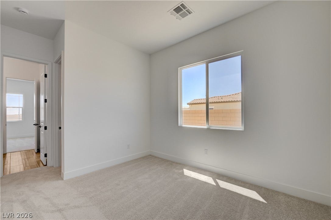 5689 Searching Bear Court, Las Vegas, NV 89149 A well-lit bedroom with plush carpeting and a bright window offering neighborhood views.