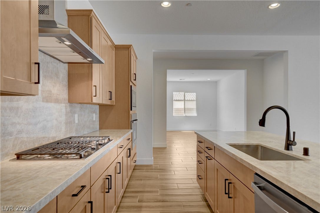 5689 Searching Bear Court, Las Vegas, NV 89149 A well-appointed kitchen features warm-toned cabinetry, a gas range, and a spacious island with a sink.