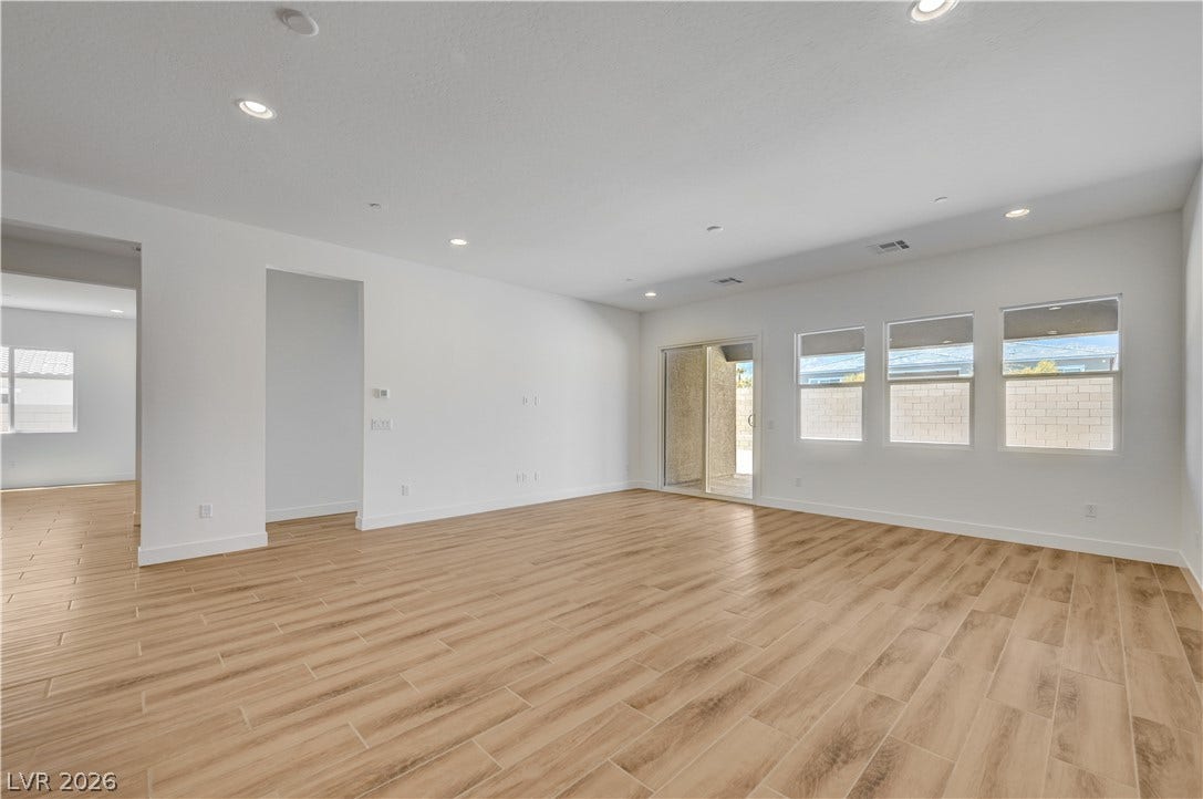 5689 Searching Bear Court, Las Vegas, NV 89149 A spacious, open-concept interior featuring light wood-look flooring and multiple windows, inviting ample daylight.