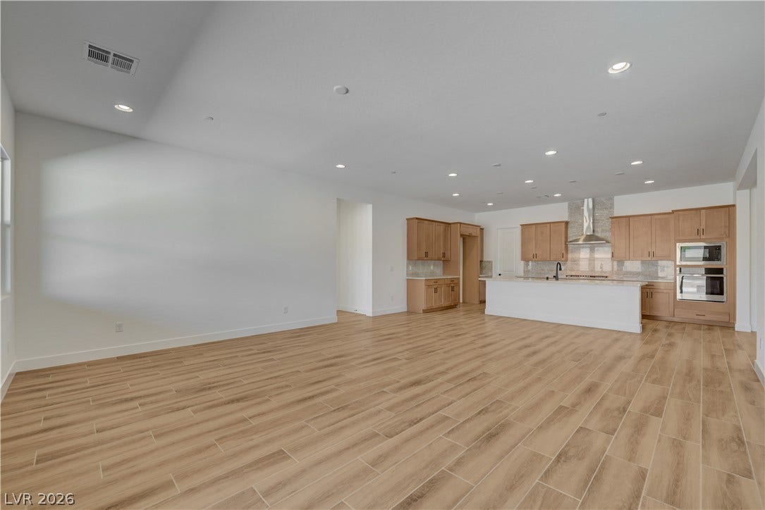 5689 Searching Bear Court, Las Vegas, NV 89149 An open-concept living space with warm wood-look flooring flows into a modern kitchen, ideal for entertaining.