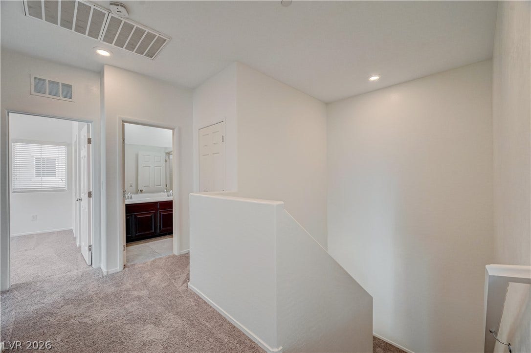 2455 Sunflower Days Avenue, #1056, North Las Vegas, NV 89031 An upper-level hallway features carpeted flooring and recessed lighting near the staircase.
