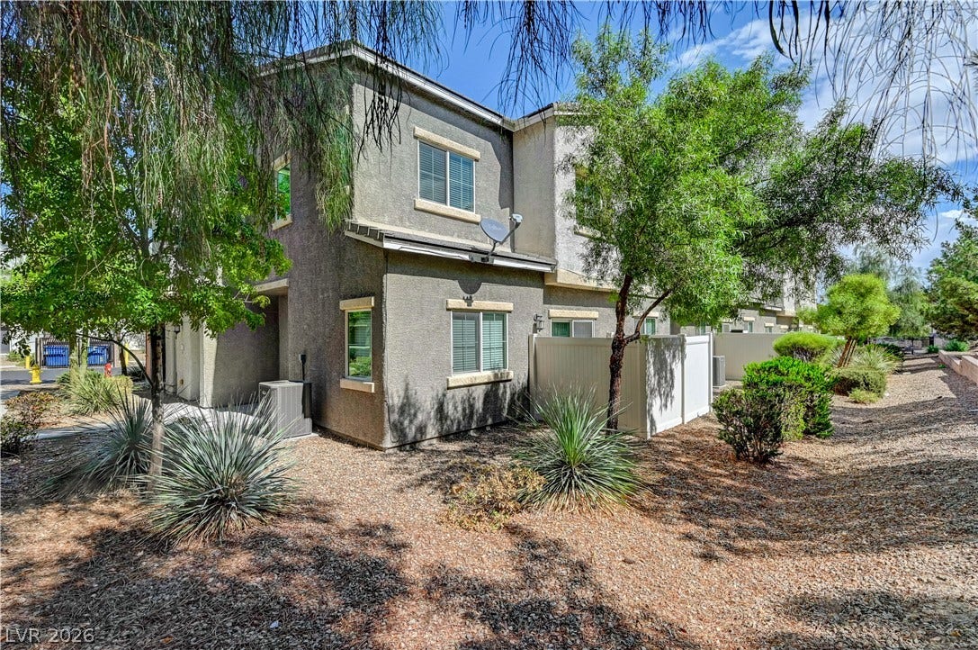 2455 Sunflower Days Avenue, #1056, North Las Vegas, NV 89031 Mature trees and low-maintenance desert plantings frame the multi-level stucco exterior.