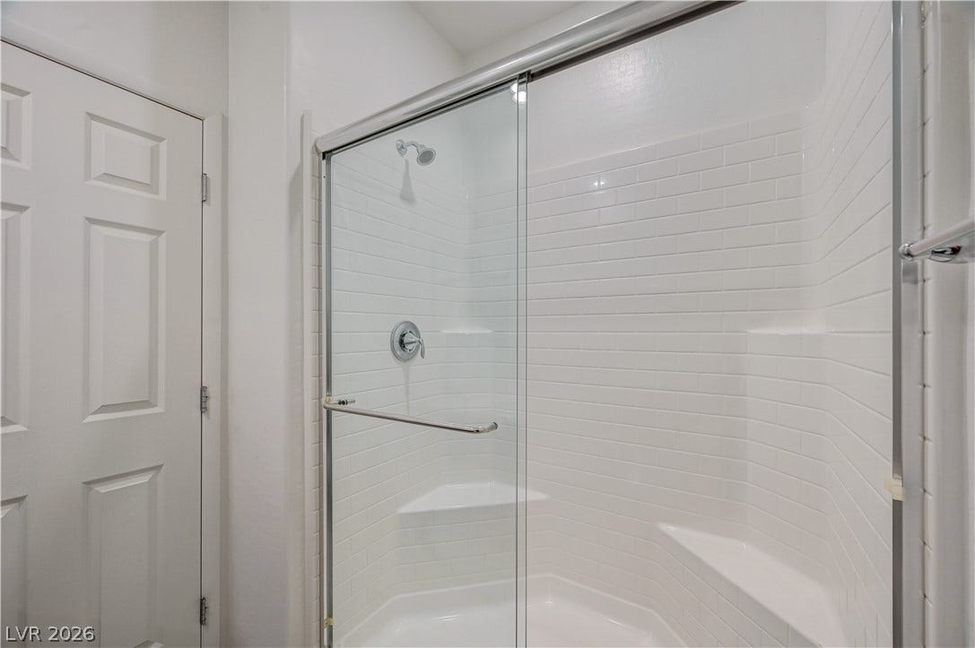 2455 Sunflower Days Avenue, #1056, North Las Vegas, NV 89031 A glass-enclosed shower showcases crisp white subway tiling and built-in bench seating.