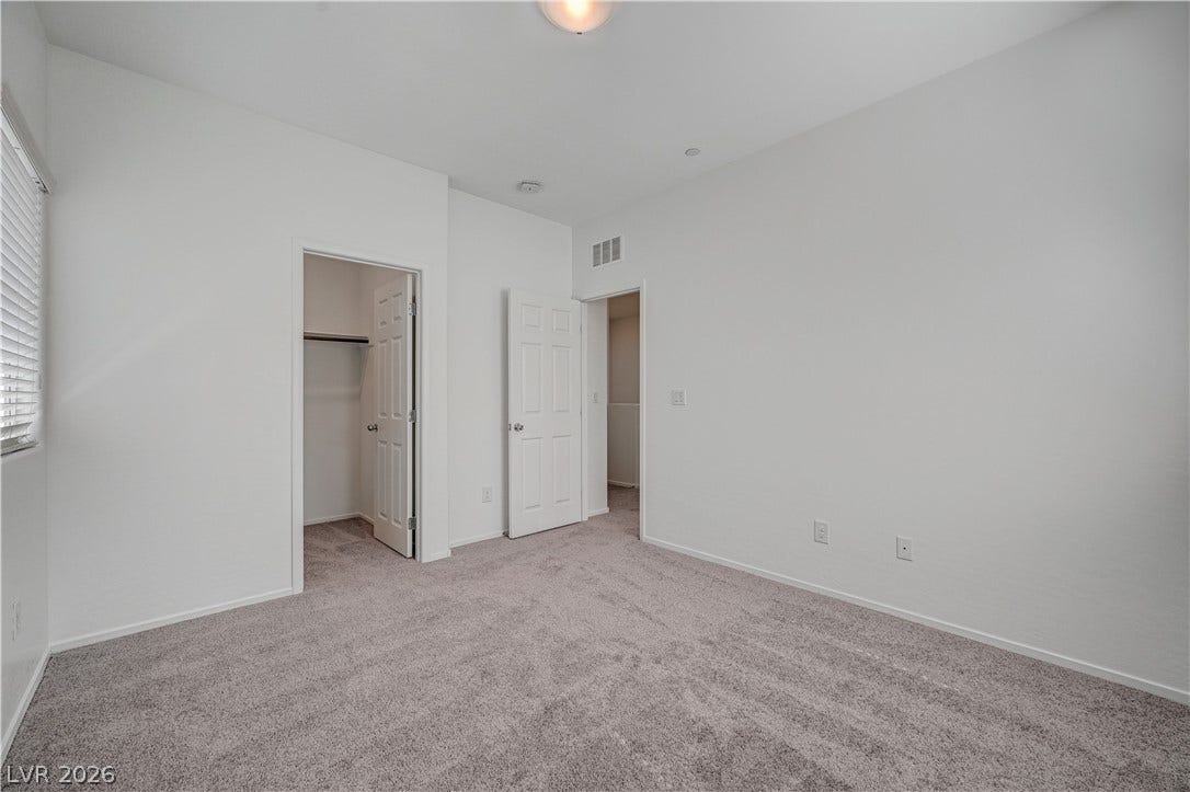 2455 Sunflower Days Avenue, #1056, North Las Vegas, NV 89031 Plush wall-to-wall carpeting and clean white walls anchor this quiet bedroom space.