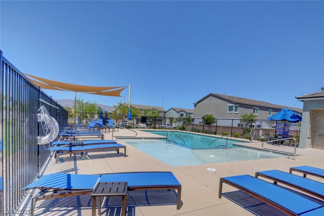 2455 Sunflower Days Avenue, #1056, North Las Vegas, NV 89031 A fenced community swimming pool features concrete decking and mountain views under clear blue skies.