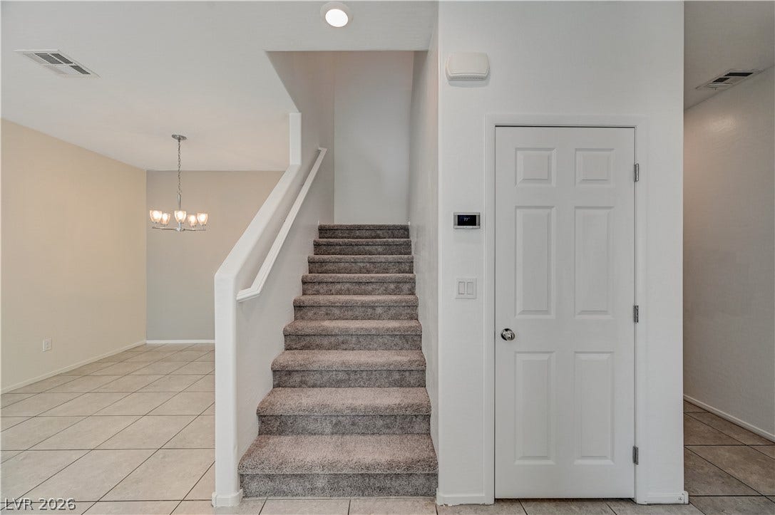 2455 Sunflower Days Avenue, #1056, North Las Vegas, NV 89031 Carpeted stairs ascend near a tiled hallway with a classic panel door.