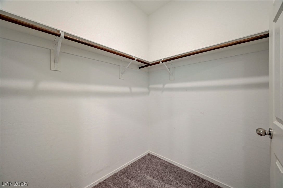 2455 Sunflower Days Avenue, #1056, North Las Vegas, NV 89031 A spacious walk-in closet features plush carpeting and integrated hanging rods with overhead shelving.