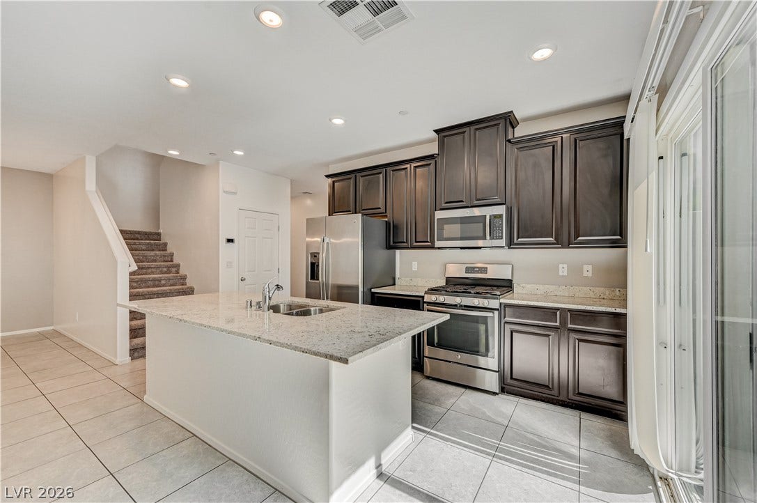 2455 Sunflower Days Avenue, #1056, North Las Vegas, NV 89031 Polished granite countertops and classic dark cabinetry anchor this open culinary space.