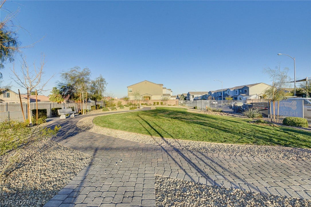2455 Sunflower Days Avenue, #1056, North Las Vegas, NV 89031 An inviting paved path curves through a manicured community park under clear blue skies.