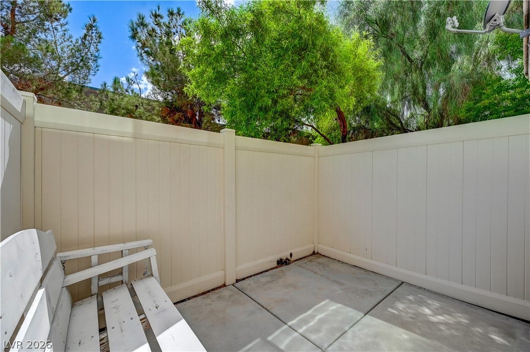 2455 Sunflower Days Avenue, #1056, North Las Vegas, NV 89031 A secluded concrete patio is enclosed by high privacy fencing and shaded by mature trees.
